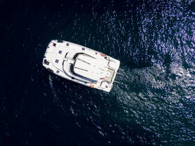Aerial view of a sleek yacht cruising through shimmering waters, showcasing its elegant design and perfect for luxury charters.