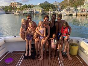 A joyful family poses together on a boat, capturing a memorable moment of fun and togetherness in a beautiful marina setting.