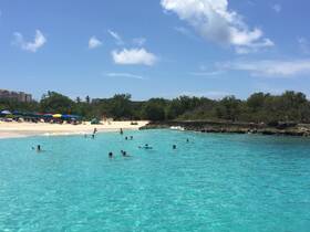 A vibrant scene of beachgoers enjoying the crystal-clear turquoise waters, perfect for swimming and relaxation on a sunny day.
