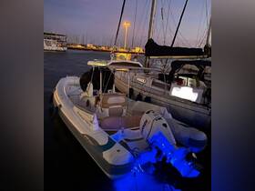 A sleek speedboat docked at night, illuminated by blue lights, showcasing its elegant design against the backdrop of a marina.