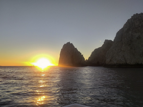 A breathtaking sunset over the coastline, with the sun casting a golden glow on the water — a perfect moment for scenic boat trips.