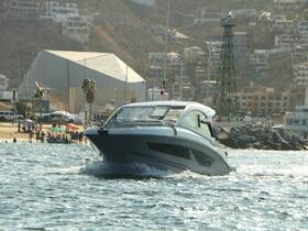 A sleek speedboat navigates the waters, showcasing its elegant design against a backdrop of coastal buildings and beachgoers.
