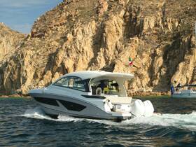 A sleek speedboat navigates through clear waters, showcasing its elegant design against a backdrop of rugged cliffs — perfect for thrilling adventures on the water.