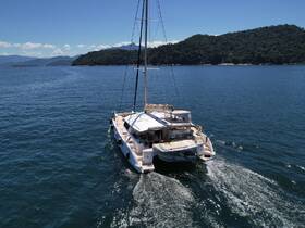 A stunning aerial view of a catamaran cruising through clear blue waters, surrounded by lush green hills — perfect for exploring coastal destinations.