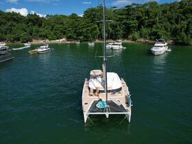 A stunning aerial view of a catamaran anchored in a serene bay, surrounded by lush greenery and other boats — perfect for exploring coastal destinations.
