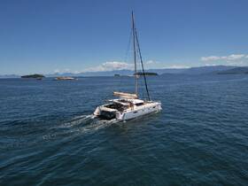 A stunning aerial view of a catamaran cruising through clear blue waters, surrounded by picturesque islands — perfect for exploring coastal destinations.