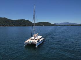 A stunning aerial view of a catamaran sailing through calm waters, surrounded by lush green hills — perfect for exploring coastal destinations.