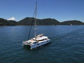 A stunning aerial view of a catamaran named 'Oceanea' cruising through calm waters, surrounded by lush green hills — perfect for exploring coastal destinations.
