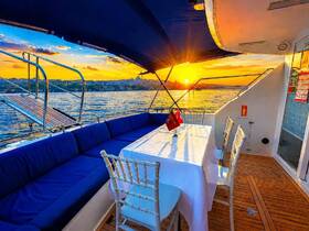 A beautifully arranged dining area on a boat, featuring plush seating and a stunning sunset view over the water — perfect for intimate gatherings or sunset cruises.