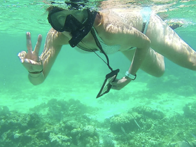 A snorkeler poses underwater, flashing a peace sign amidst vibrant marine life — a perfect snapshot of adventure and exploration in the ocean.