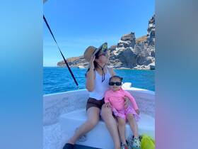 A joyful moment captured on a boat, featuring a mother and her daughter enjoying the sunny ocean views — perfect for family outings and adventures on the water.