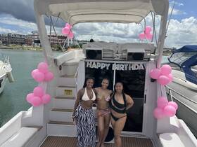 Three friends celebrate a birthday aboard a decorated boat, complete with festive balloons — a perfect setting for memorable boat parties.