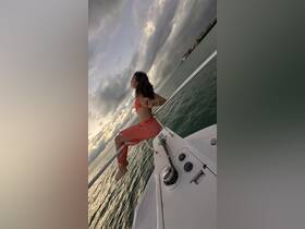 A woman relaxes on the bow of a boat, enjoying the serene sunset over the water — a perfect moment for capturing the essence of a boating adventure.