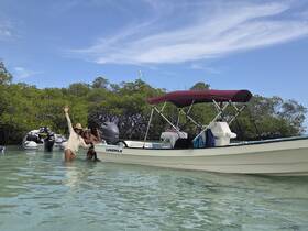 Two friends enjoy a fun day in the water near their boat, celebrating amidst the lush mangroves — a perfect setting for adventure and relaxation.