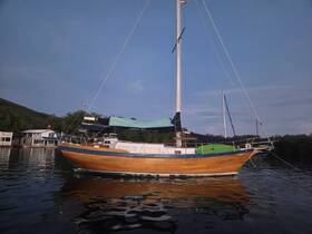 A beautifully crafted sailboat docked in calm waters, showcasing its elegant wooden hull and serene surroundings — perfect for sailing enthusiasts.