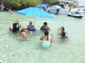 A lively group enjoys drinks and fun in shallow waters at a sandbar, creating the perfect atmosphere for a summer party on the water.