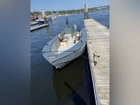 A small boat docked at a marina, showcasing its simple design and seating arrangement, ideal for fishing or leisurely outings on the water.
