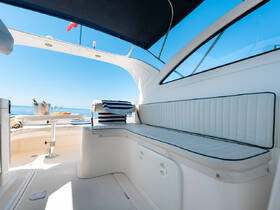 A spacious and inviting interior seating area on a boat, featuring comfortable cushions and a table, perfect for relaxing while enjoying the ocean views.