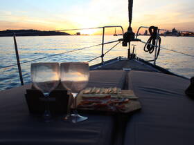 A serene sunset view from a yacht featuring two glasses and a charcuterie board, perfect for a relaxing evening on the water.