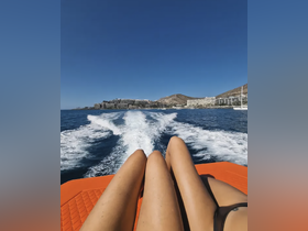 Two friends relax on the edge of a boat, enjoying the ocean view and the thrill of the ride — a perfect snapshot of a sunny day on the water.