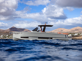 A sleek yacht is captured underway against a stunning backdrop of mountains and clouds, showcasing the beauty of boating in scenic locations.