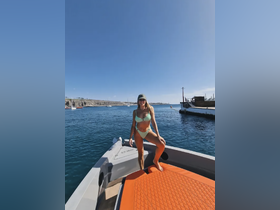 A woman poses on the deck of a boat, enjoying a sunny day on the water — perfect for summer adventures and fun outings.