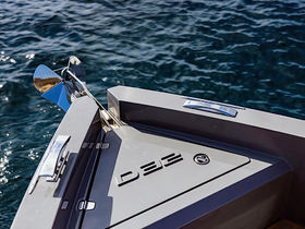 Close-up view of the bow of a sleek boat, showcasing its design and craftsmanship against a shimmering water backdrop.