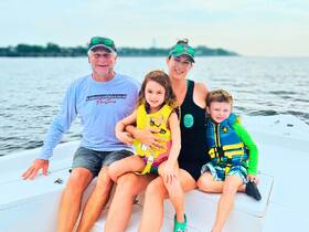 A joyful family enjoys a day on the water, with kids wearing life jackets while sitting on the boat — perfect for summer adventures and family bonding.