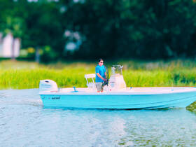 A man navigates a Bulls Bay boat through serene waters, showcasing the perfect setting for fishing or leisurely outings.