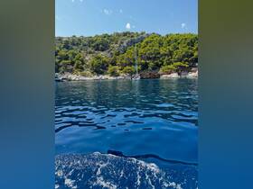 A serene view of a yacht anchored near a lush coastline, showcasing the beauty of sailing in tranquil waters.