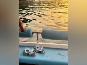 A close-up of snorkel gear resting on the deck of a boat, with a hand visible in the background, set against a stunning sunset over the water — perfect for underwater adventures.