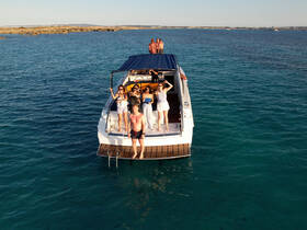 A lively group enjoys a fun day on the water, celebrating aboard a boat with stunning turquoise waters in the background — perfect for summer gatherings and parties.