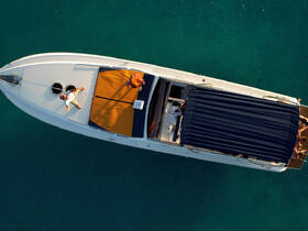 Aerial view of guests enjoying the sun on a boat, showcasing a perfect day on the water with clear turquoise surroundings.