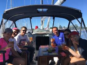 A cheerful group enjoys cocktails aboard a sailboat, celebrating together in a vibrant marina setting — perfect for social gatherings and sailing adventures.