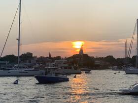 A picturesque sunset over a harbor filled with boats, creating a serene backdrop perfect for evening cruises and waterfront relaxation.