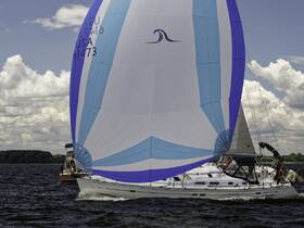 A vibrant sailboat with a colorful spinnaker sails through the water, showcasing the beauty of sailing on a sunny day.