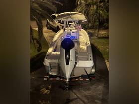 A sleek speedboat is parked in a driveway, showcasing its streamlined design and features under the night lights, perfect for evening adventures on the water.