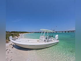 A sleek speedboat rests on a sandy shore, surrounded by crystal-clear waters, ideal for fishing or day trips in the sun.