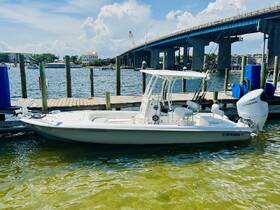 A sleek center console boat named 'Contender' docked at the marina, showcasing its pristine design against a backdrop of calm waters and a blue sky.