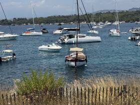 A picturesque scene of various boats anchored in a serene bay, with a swimmer enjoying the clear waters — perfect for a relaxing day on the water.