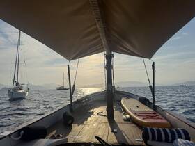A serene view from the interior of a boat, showcasing the helm area and paddleboard, perfect for relaxing on the water.