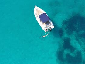 A couple enjoys a refreshing swim in the crystal-clear turquoise waters beside their boat, capturing the essence of a perfect day on the water.