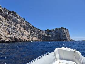 A scenic view from the bow of a boat navigating along a rugged coastline, showcasing the stunning cliffs and deep blue waters — perfect for exploring hidden coves and coastal adventures.