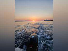 A stunning sunset view from a boat, showcasing the tranquil waters and distant hills — perfect for evening cruises.