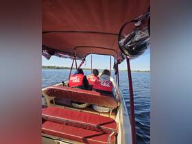 A cozy interior view of a boat with guests seated in life jackets, enjoying a scenic ride on the water.