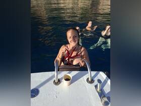 A woman joyfully holds an octopus while enjoying a swim, surrounded by friends in the clear blue waters — a memorable marine encounter during a fun day on the water.