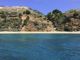 A picturesque view of a serene beach surrounded by lush cliffs and clear blue waters, perfect for a relaxing day on the coast.