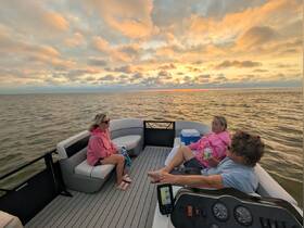 A group enjoys a serene sunset on a pontoon boat, capturing the essence of relaxation and camaraderie on the water.