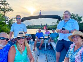 A cheerful group enjoys a sunset cruise on a boat, capturing moments of friendship and fun on the water.