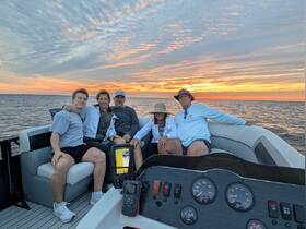 A joyful family gathers on a boat at sunset, capturing a memorable moment together on the water — perfect for family outings and celebrations.